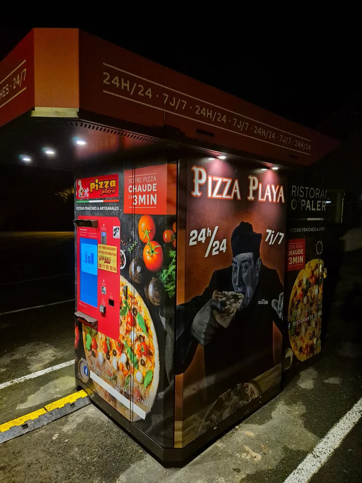 Distributeur automatique de pizzas illuminé la nuit